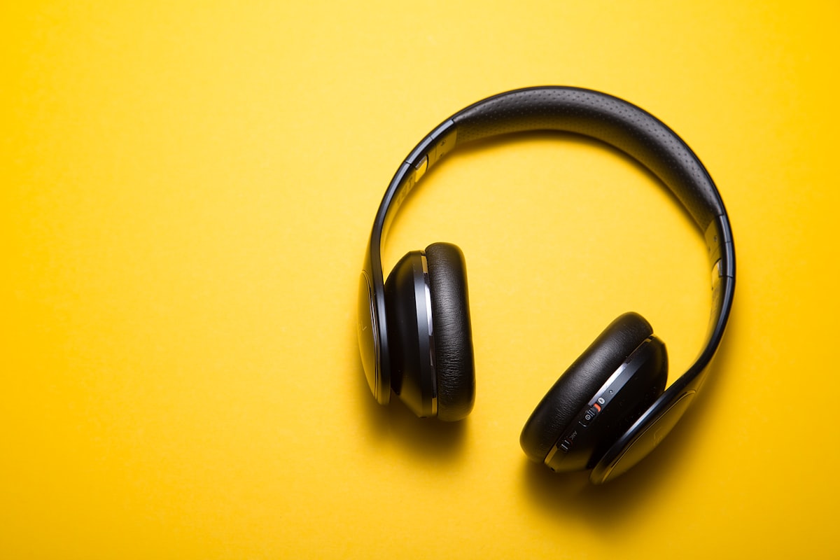 Person working productively at desk with headphones listening to music on laptop