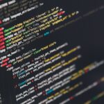 Developer comparing AI coding assistants Claude and ChatGPT on dual monitors with code on screen