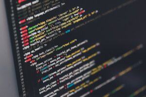 Developer comparing AI coding assistants Claude and ChatGPT on dual monitors with code on screen