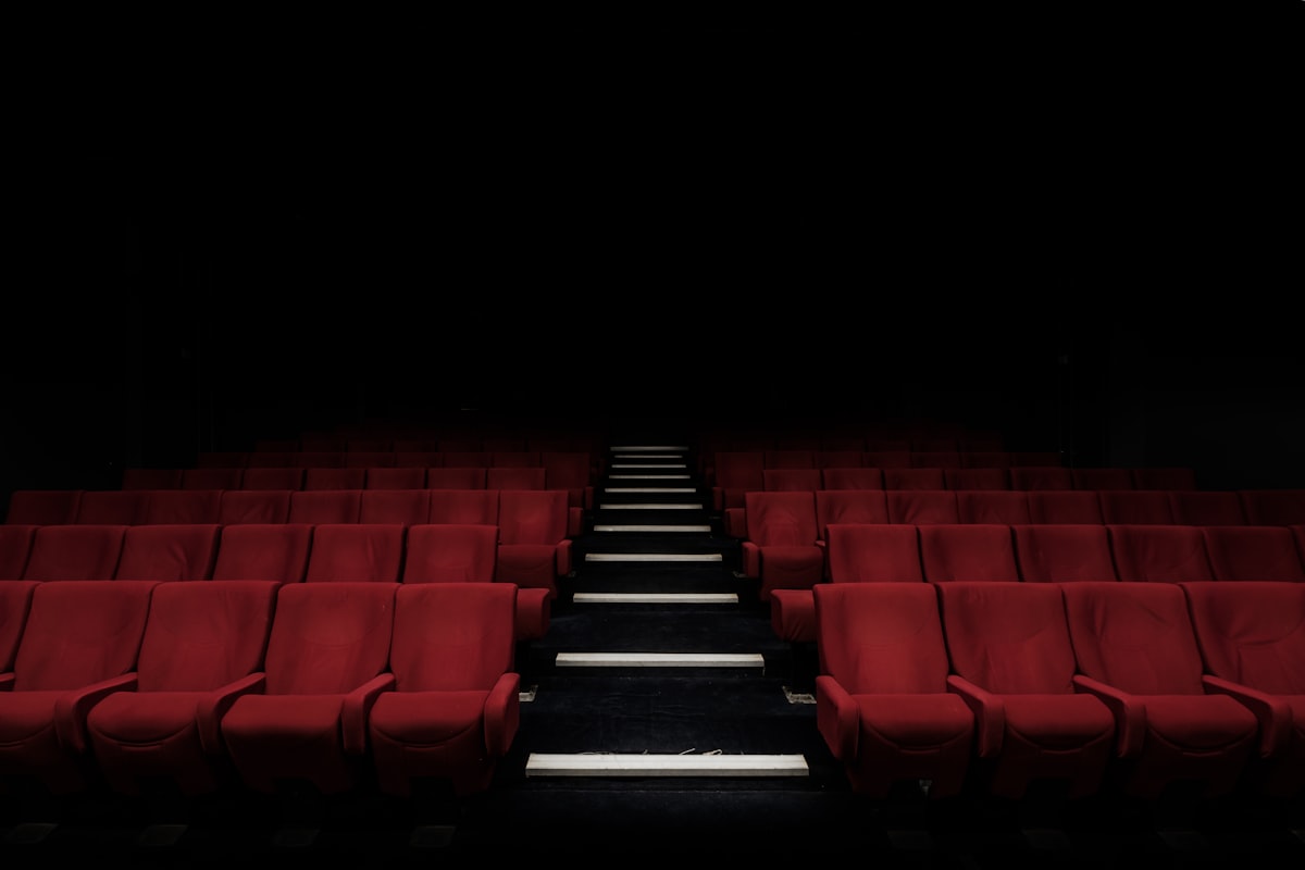 Cinematic film reel and popcorn with glowing movie screen in a dark theater representing viral movies 2026