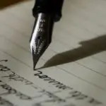 Writer using AI software on laptop to create and edit ebook manuscript with books in background