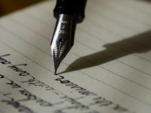 Writer using AI software on laptop to create and edit ebook manuscript with books in background